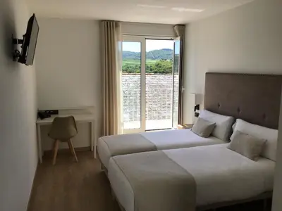 a bedroom with a bed and a large window at VISTALEGRE Hotel-Spa in Portomarin