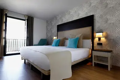 a bedroom with a large white bed with blue pillows at VISTALEGRE Hotel-Spa in Portomarin