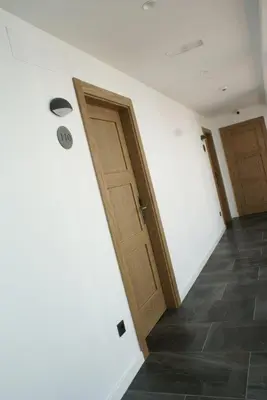a hallway with two wooden doors and a tile floor at VISTALEGRE Hotel-Spa in Portomarin