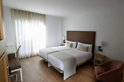 a bedroom with a large white bed and a window at VISTALEGRE Hotel-Spa in Portomarin