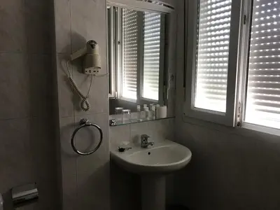 a bathroom with a sink and a window at Pensión Portomiño in Portomarin