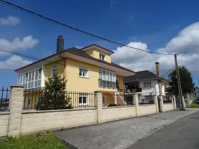 a yellow house with a fence on a street at Apartamento Apega in Ribadeo