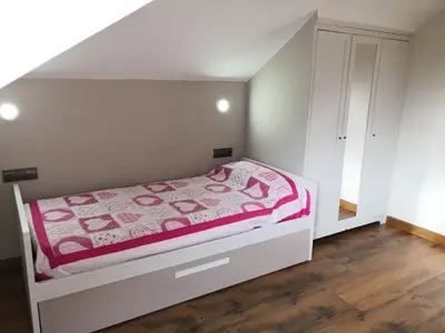 a small bedroom with a bed with a pink blanket at Apartamento Apega in Ribadeo