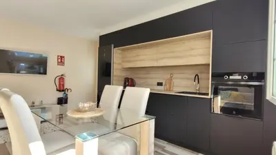 a kitchen with a glass table and white chairs at Besbello Suites - Apartamento in Santiago de Compostela