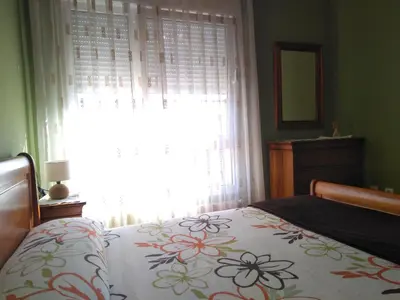 a bedroom with a bed with a flowered blanket and a window at El piso de Carlos in Ribadeo