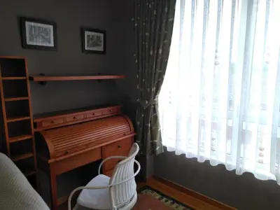 a bedroom with a wooden desk and a window at El piso de Carlos in Ribadeo