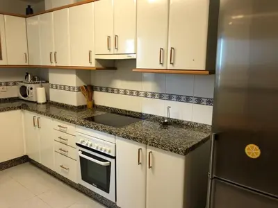 a kitchen with white cabinets and a stainless steel refrigerator at El piso de Carlos in Ribadeo