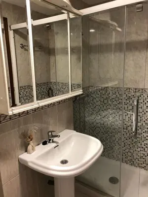 a bathroom with a sink and a glass shower at El piso de Carlos in Ribadeo