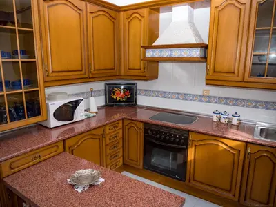 a kitchen with wooden cabinets and a microwave at Casa rural quiroga in Portela