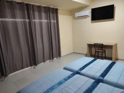 a bedroom with two beds and a desk and a television at Hotel Novo in Ponferrada