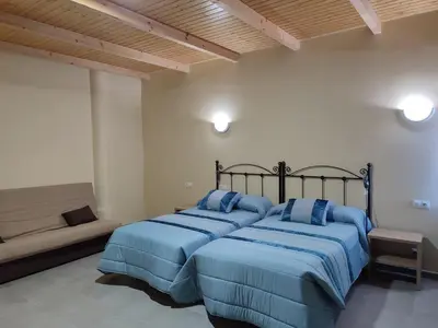 a bedroom with two beds and a couch at Hotel Novo in Ponferrada
