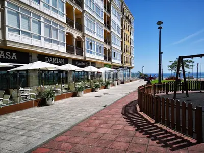 a sidewalk in front of a building with tables and umbrellas at Duplex Tres Dormitorios Playa A Rapadoira in Foz