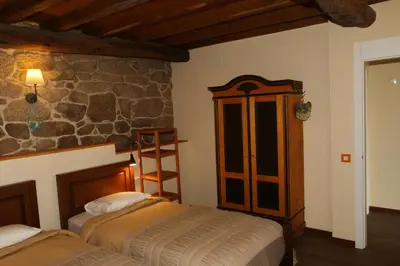 a bedroom with two beds and a stone wall at Pazo de Chaioso Ribeira Sacra in Maceda