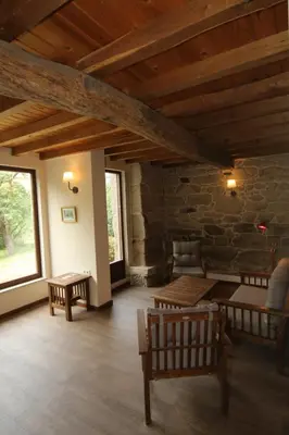 a living room with wooden furniture and a stone wall at Pazo de Chaioso Ribeira Sacra in Maceda