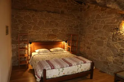 a bedroom with a bed in a stone wall at Pazo de Chaioso Ribeira Sacra in Maceda