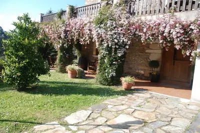 a garden with pink flowers on a building at Lugar do Sixto in Cordido