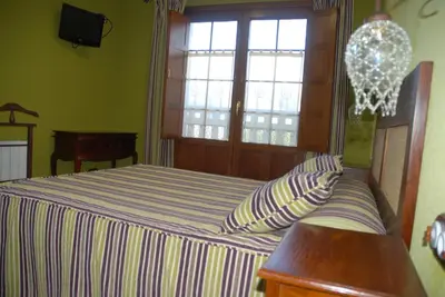 a bedroom with a bed with a table and a window at Lugar do Sixto in Cordido