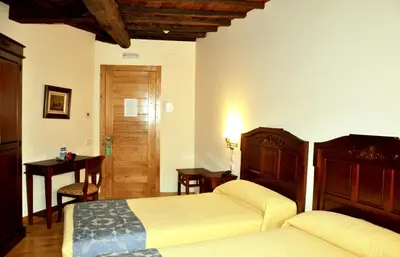 a bedroom with two beds and a table and a door at PR San Nicolás in Santiago de Compostela