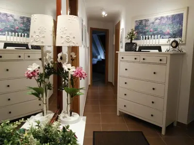 a room with white dressers and flowers in it at San Ciprian Atico Tres Playas by I Love Norte in San Ciprián
