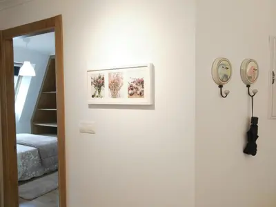 a white wall with a picture and a clock on it at San Ciprian Atico Tres Playas by I Love Norte in San Ciprián