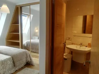 a bathroom with a sink and a bed and a mirror at San Ciprian Atico Tres Playas by I Love Norte in San Ciprián
