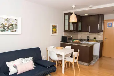 a living room with a couch and a table and a kitchen at Luminoso Termal Casco Histórico in Ourense