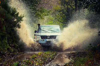 a car driving through a puddle of water on a dirt road at Hotel Rural Las Montañas de Pumar in Besullo