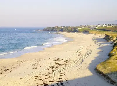 a beach with footprints in the sand and the ocean at Monqar Playa Foz in Foz