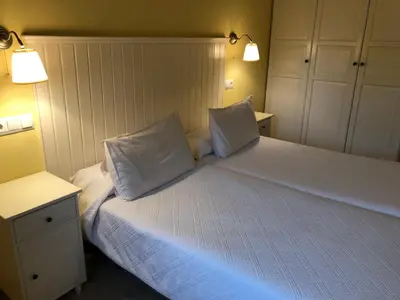 a bedroom with a white bed with two pillows at Apartamentos El Guindal in Tapia de Casariego