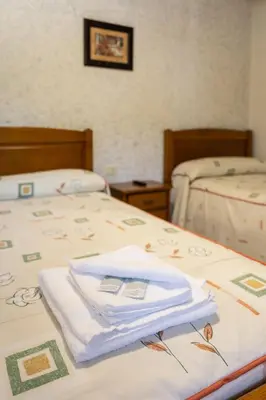 a room with two beds with towels on them at Hostal Sequeiros in San Ciprián de Viñas