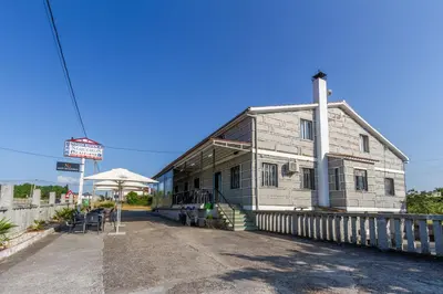 an old building with an umbrella and a table and chairs at Hostal Sequeiros in San Ciprián de Viñas