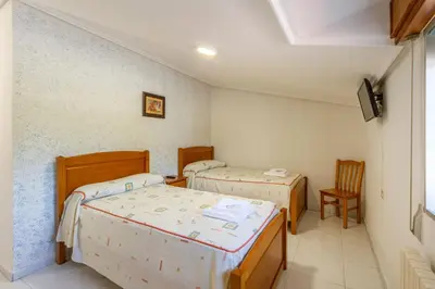 a room with two beds and a chair at Hostal Sequeiros in San Ciprián de Viñas