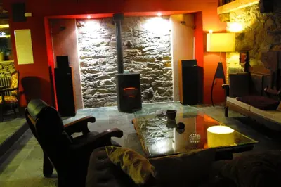 a living room with a table and a stone wall at Casa Turismo Rural O FILANDÓN in Suertes