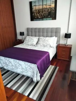 a bedroom with a large bed with a purple blanket at apartment garden in Caldas de Reis