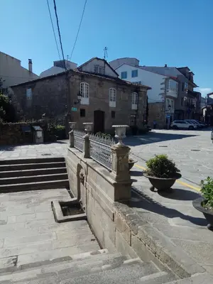 a stone wall with some plants on a street at apartment garden in Caldas de Reis