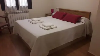 a white bed with red pillows and towels on it at Camino Real in Molinaseca