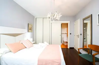 a bedroom with a white bed and a chandelier at Pension As Burgas Ii in Caldas de Reis