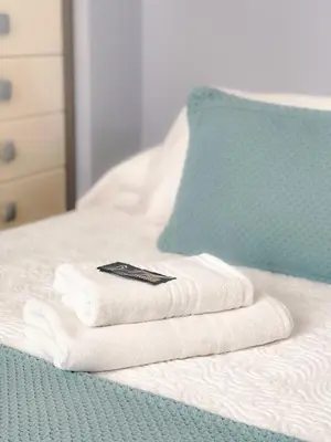 a pile of towels sitting on top of a bed at Pension As Burgas Ii in Caldas de Reis