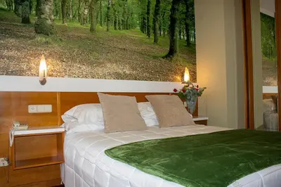a bedroom with a bed with a painting on the wall at Hotel Bello in O Pino
