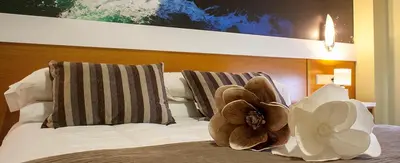 a bed with pillows and a flower on it at Hotel Bello in O Pino