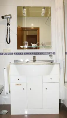 a bathroom with a white sink and a mirror at Hotel Bello in O Pino