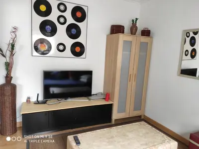 a living room with a tv and a cabinet with records at La Mariña in Ribadeo