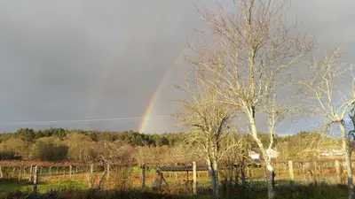 a rainbow in the sky over a field with trees at casa cacheiras in Teo