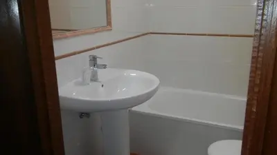 a white bathroom with a sink and a bath tub at Hostal-Meson Vilasante in Tríacastela