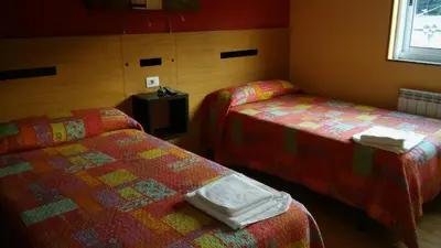 a hotel room with two beds and a window at Hostal-Meson Vilasante in Tríacastela