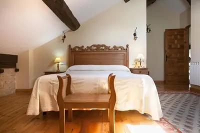 a bedroom with a bed and a wooden chair at Paraiso del Bierzo in Las Herrerías