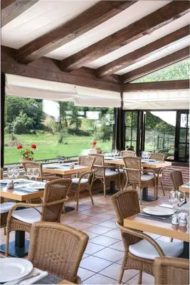 a restaurant with wooden tables and chairs and windows at Paraiso del Bierzo in Las Herrerías