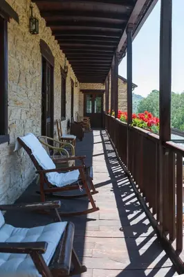 a porch with rocking chairs and flowers on a building at Paraiso del Bierzo in Las Herrerías