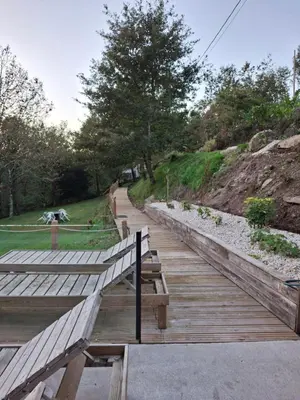 a wooden boardwalk with benches on the side of a hill at A Pontiga I Casa Rural in Mezonzo