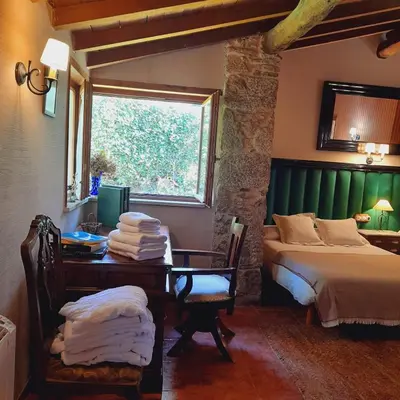 a bedroom with a bed and a desk and a window at A Pontiga I Casa Rural in Mezonzo